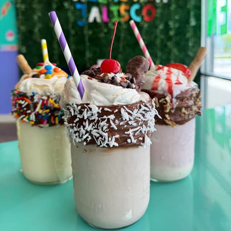 Three Jalisco Mexican Ice Cream milkshakes, topped with whipped cream, sprinkles, chocolate, and cherries.